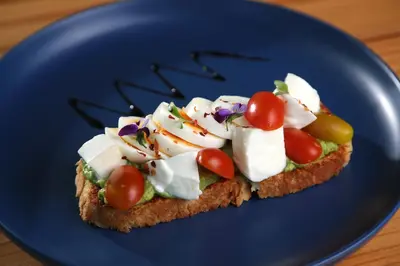 a piece of bread with vegetables on a blue plate at OPacifico Hotel Boutique in Playa Naranjo