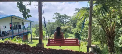 a woman sitting on a bench looking out at the forest at Volcano Panoramic Views in Vara Blanca