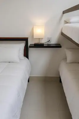 two beds in a room with a lamp on the wall at Volcano Panoramic Views in Vara Blanca