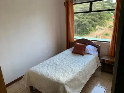 a small bed in a room with a window at Globi Lodge #4 in Monteverde Costa Rica