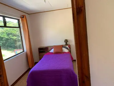 a bedroom with a purple bed and a window at Globi Lodge #4 in Monteverde Costa Rica