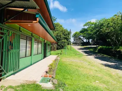 a green building with a sidewalk next to a street at Globi Lodge #4 in Monteverde Costa Rica