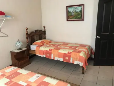 a bedroom with two beds and a picture on the wall at Casa del Suizo in Alajuela City