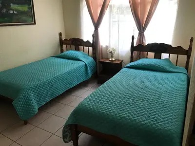 a bedroom with two beds and a window at Casa del Suizo in Alajuela City