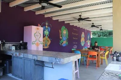 a kitchen with a table and a person sitting at a table at Planet B Hostel - Adults Only in Manuel Antonio