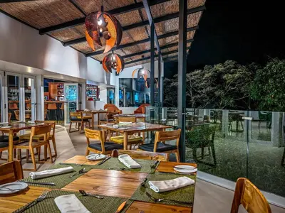 a restaurant with wooden tables and chairs and a large window at Monteverde Lodge by Böëna in Monteverde Costa Rica