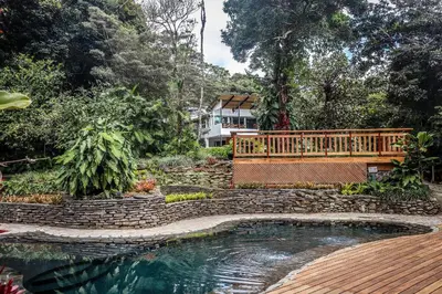 a wooden bench sitting next to a swimming pool at Monteverde Lodge by Böëna in Monteverde Costa Rica