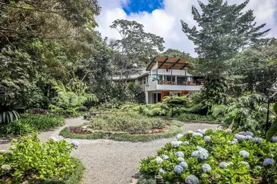 a house in the middle of a garden with flowers at Monteverde Lodge by Böëna in Monteverde Costa Rica