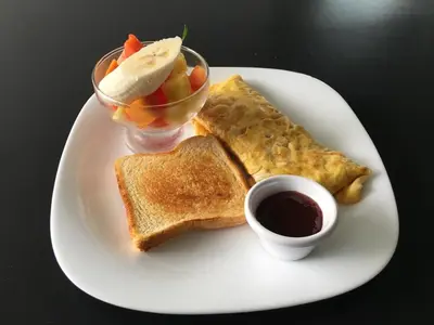 a white plate of food with toast and a bowl of fruit at Hotel Monte Real in Fortuna