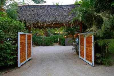 a building with orange doors and a thatched roof at Living Hotel in Nosara