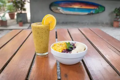 a bowl of food and a drink on a wooden table at Living Hotel in Nosara