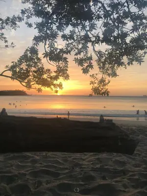 a sunset on a beach with people in the water at Casa Papito in Potrero