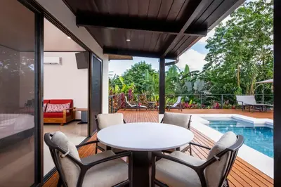 a patio with a table and chairs and a pool at Arenal Manoa Resort & Hot Springs in Fortuna
