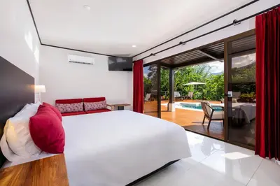 a bedroom with a white bed and a view of a pool at Arenal Manoa Resort & Hot Springs in Fortuna