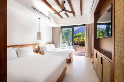 a hotel room with two beds and a balcony at Arenal Manoa Resort & Hot Springs in Fortuna
