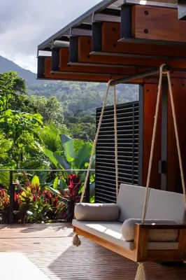 a swing on a deck with a view of the mountains at Arenal Manoa Resort & Hot Springs in Fortuna