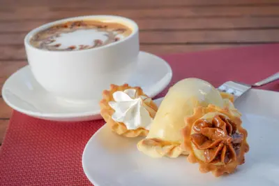 a white plate with a pastry and a cup of coffee at La Riviera Hotel in San José