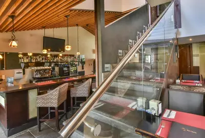 a bar in a restaurant with a counter and chairs at La Riviera Hotel in San José