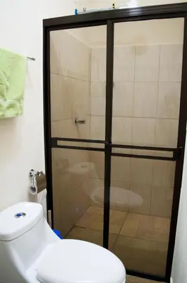 a bathroom with a glass shower door next to a toilet at Guesthouse Casa Lapa2 in Alajuela City