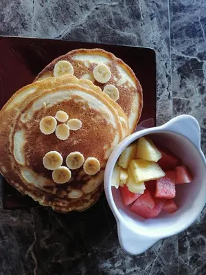 two pancakes with bananas and strawberries next to a bowl of fruit at Monteverde Ecolove in Monteverde Costa Rica