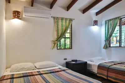 two beds in a room with two windows at Villas Macondo in Tamarindo