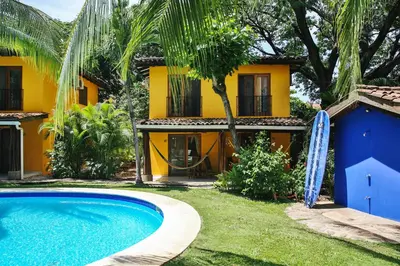 a villa with a swimming pool in front of a house at Villas Macondo in Tamarindo