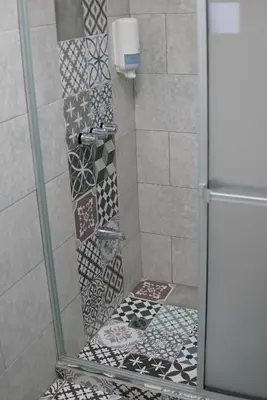 a shower with a glass door with mosaics at NATIVUS Art-Hostel in San José