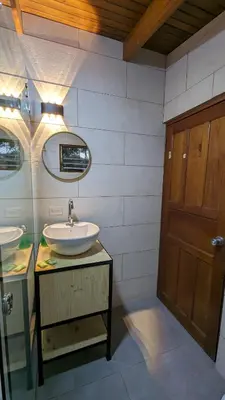 a bathroom with a sink and a wooden door at Mangifera Hostel in Grecia