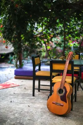 a guitar sitting next to a table and chairs at Mangifera Hostel in Grecia