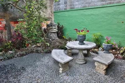 a stone table with two chairs and a statue at Mangifera Hostel in Grecia