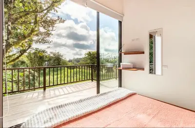 a bedroom with a balcony with a large window at Puma Meraki Mountain View Monteverde in Monteverde Costa Rica