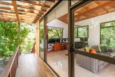 an open living room with glass doors and a couch at Puma Meraki Mountain View Monteverde in Monteverde Costa Rica