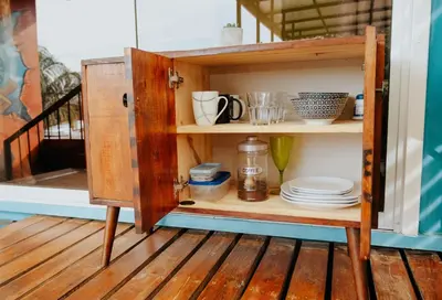 an open cabinet with plates and dishes in it at Wanderlust in Jacó