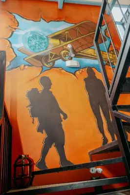 a painting of a man and a plane on a wall at Wanderlust in Jacó