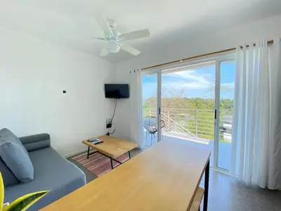 a living room with a couch and a sliding glass door at Altamar in Santa Teresa Beach