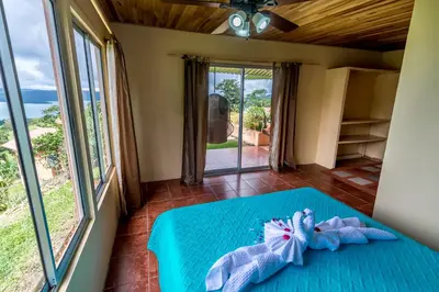 a bedroom with a blue bed with a view at Hotel Nepenthe B&B in El Castillo de La Fortuna