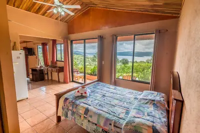 a bedroom with a bed and a large window at Hotel Nepenthe B&B in El Castillo de La Fortuna