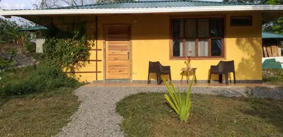 a yellow house with chairs and a table in front of it at Hotel Rio Celeste Finca L´ Etoile Celeste in El Achiote
