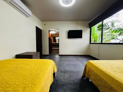 a bedroom with two beds and a television in it at Arenal Backpackers Resort in Fortuna