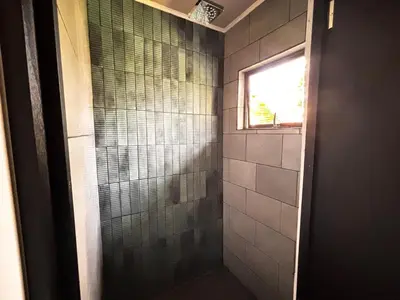 a bathroom with a glass shower with a window at Arenal Backpackers Resort in Fortuna