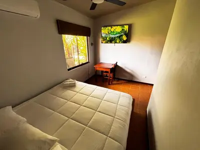 a bedroom with a bed and a desk with a window at Arenal Backpackers Resort in Fortuna