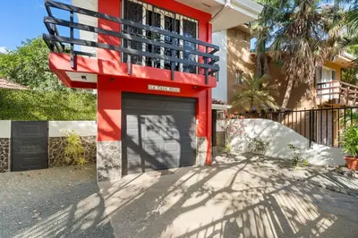 a red building with a garage in front of a building at Spacious Home with Private Pool & Covered Patio Near the Beach in Playa Flamingo