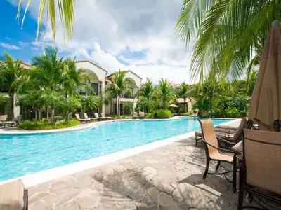 a swimming pool with palm trees and a resort at Nicely Decorated Ground-Floor Unit in Front of Pool at Pacifico in Coco in Coco