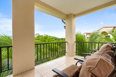 a balcony with a view of the ocean and palm trees at Renovated Condo in High-End Resort Community with Spectacular Mountain Views, Modern Design, and Beach Club Access in Coco