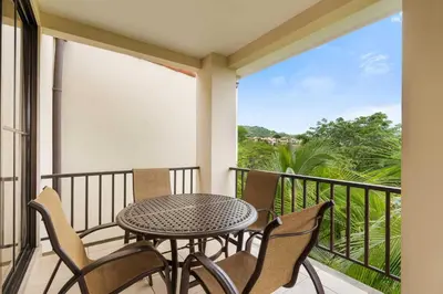 a patio with a table and chairs on a balcony at Renovated Condo in High-End Resort Community with Spectacular Mountain Views, Modern Design, and Beach Club Access in Coco