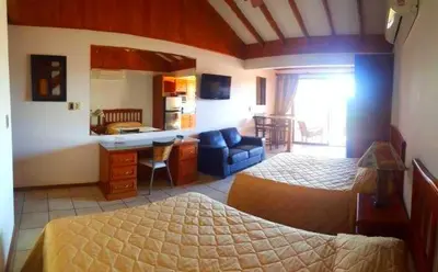 a bedroom with two beds and a couch and a kitchen at Flamingo Marina Resort Studio in Playa Flamingo