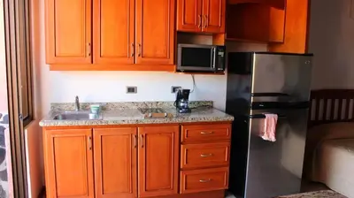 a kitchen with wooden cabinets and a stainless steel refrigerator at Flamingo Marina Resort Studio in Playa Flamingo