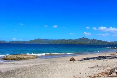 a beach with the ocean and mountains in the background at Flamingo Marina Resort Studio in Playa Flamingo