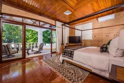 a bedroom with a bed and a balcony with a television at Blue Jewel Oceanfront Private Villa in Tamarindo