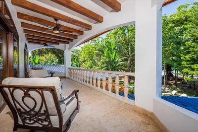 an outdoor porch with a chair and a large window at Blue Jewel Oceanfront Private Villa in Tamarindo